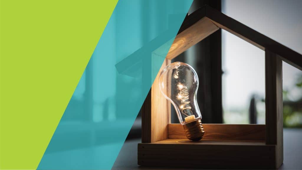 Une ampoule allumée à l'intérieur d'une petite maison en bois, symbolisant une idée brillante.