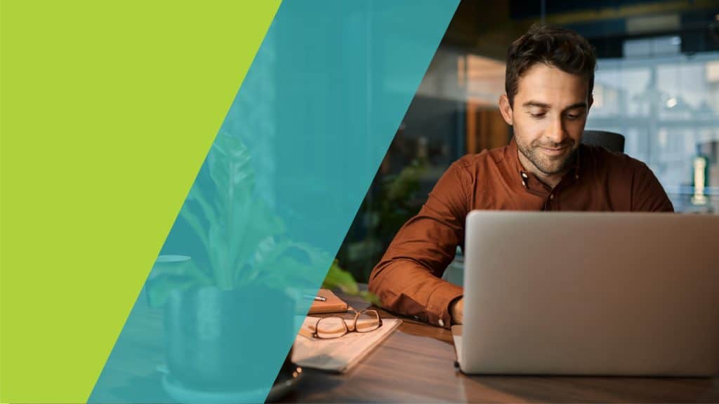 Un homme concentré travaille sur un ordinateur portable dans un environnement moderne et lumineux.