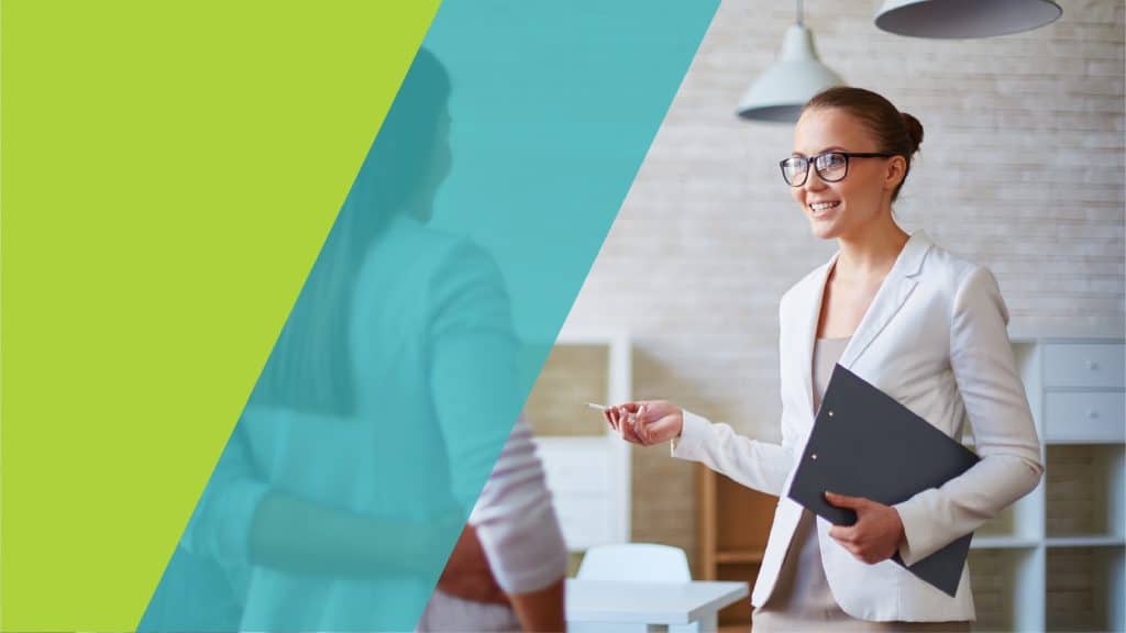 Une femme souriante et professionnelle dans un bureau moderne, en train de discuter avec une collègue tout en tenant un porte-documents.